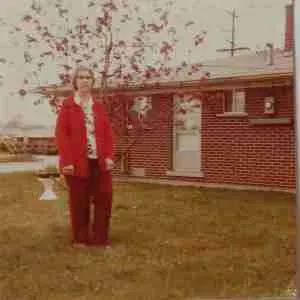 Grandmother standing on lawn outside her home