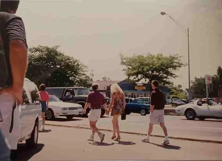 A woman in a very short skirt briefly distracts some of the men from the parade of cars.