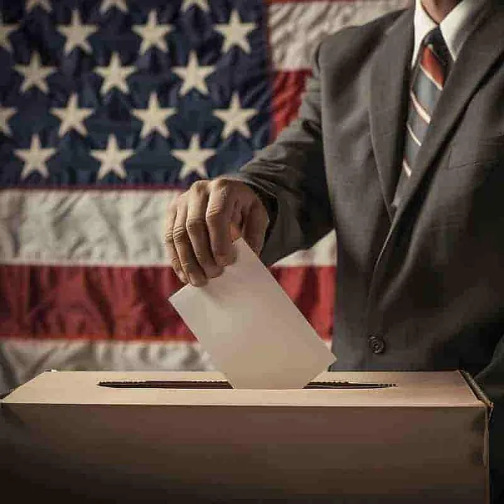 Man placing a ballot into a box through a slit in the top of the box