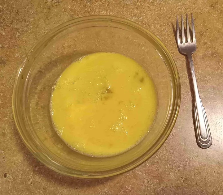 A Bowl of scrambled eggs and a fork
