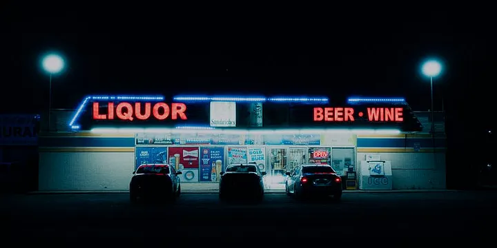 An image of a liquor store lit up at night by colorful neon signage